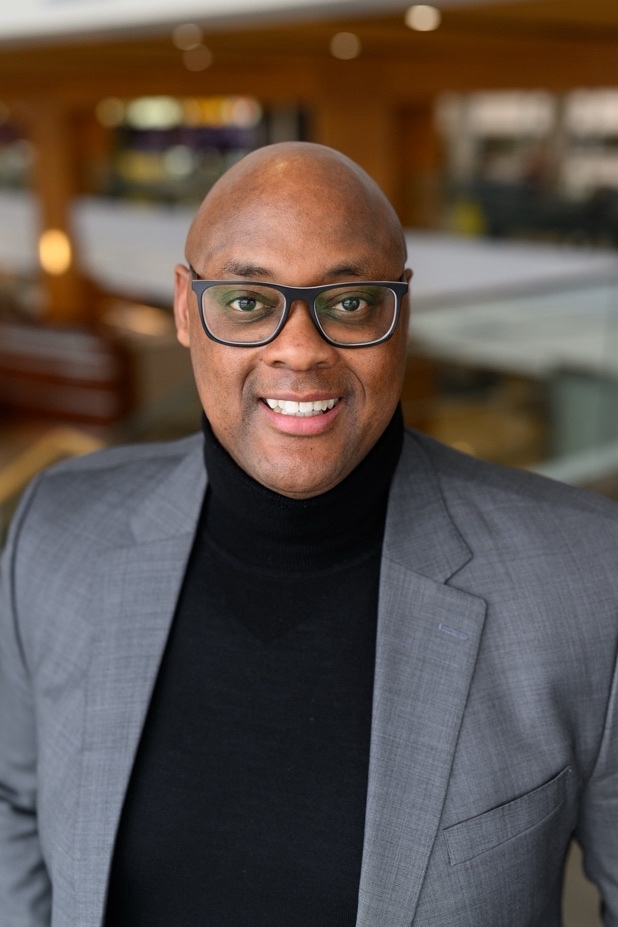 a person wearing glasses and a grey suit